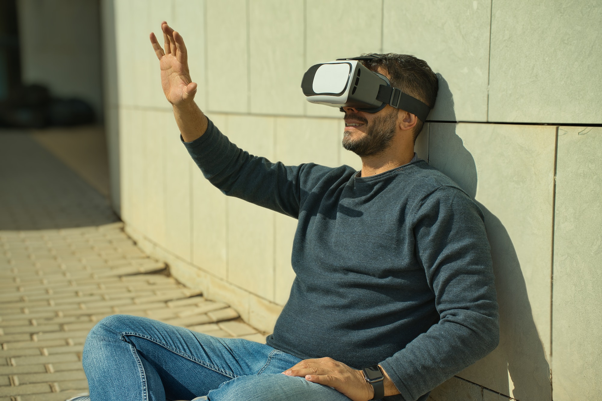 Smiling man using virtual reality (VR) glasses outdoors on a sunny day